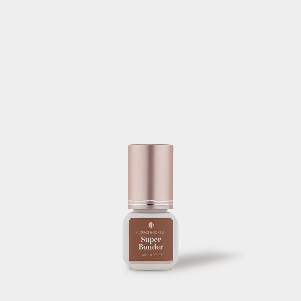BL Lashes Super Bonder curing booster for lash extensions in a small frosted glass bottle with a metallic rose gold cap, displayed on a light gray background. The brown label reads “Curing Booster Super Bonder” with the volume “5 ml / 0.17 fl. oz.” A soft shadow appears to the right, emphasizing a clean, minimal studio-style product presentation designed to accelerate adhesive curing and improve retention during eyelash extension procedures.